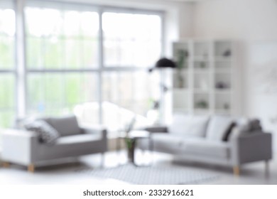 Blurred interior of light living room with grey sofas, coffee table and big window - Shutterstock ID 2332916621