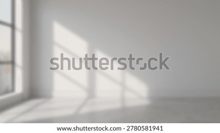A blurred interior scene features an empty room with a large window casting soft geometric shadows across a white wall and a concrete floor