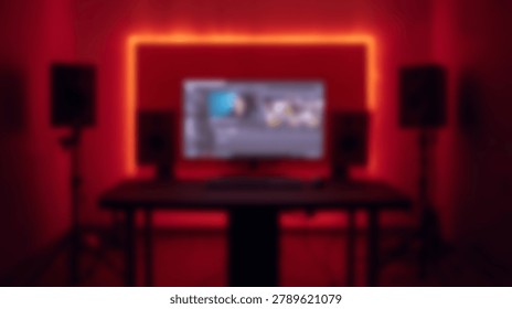 A blurred interior shot of a computer desk setup featuring a monitor and audio speakers against a wall with glowing red LED accent lighting