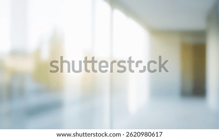 Blurred interior space with large windows and bright light.