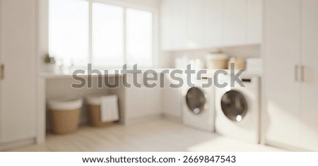 Blurred interior view of a bright laundry room with white cabinets, washing machines, baskets, and soft natural light creating a clean balanced home atmosphere.