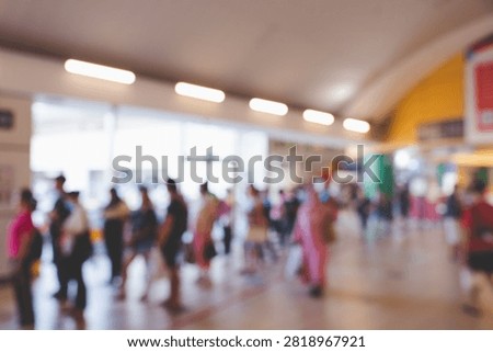 Blurred interior view of commuters queuing in line at a public transit terminal or bus interchange station.