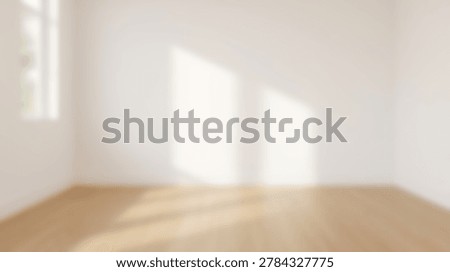 Blurred interior view of an empty room featuring white walls and light wooden flooring with soft natural sunlight casting shadows on the wall