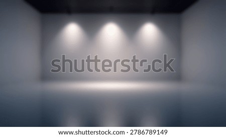 A blurred interior view of an empty studio space featuring white walls and three overhead spotlights creating soft pools of illumination