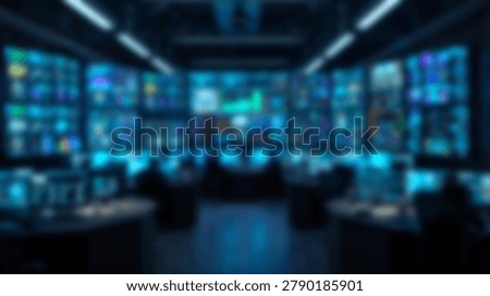 A blurred interior view of a professional command center featuring rows of computer workstations and large wall-mounted monitors displaying complex data visualizations in a dark environment.