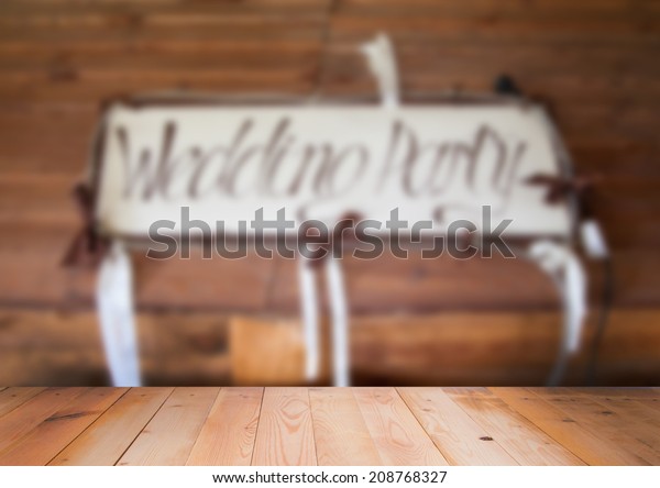 Blurred interior of wedding party sign with\
wooden surface