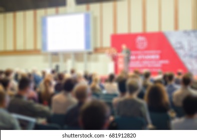 blurred international conference seminar congress with keynote speaker giving speech at podium among audiences 