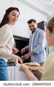 Blurred Kid With Grilled Chicken Fillet Near Mom And Smiling Dad Preparing Vegetable Salad