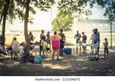 Blurred Large Group Of Friend, Family Members Enjoy Barbecue On Lakeside Area. Outdoor Camping At Natural Park With Picnic Table In Grand Prairie, Texas, USA. Outside Party And BBQ Concept