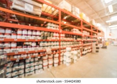 Blurred large hardware store in America. Defocused interior home improvement retailer, racks, rows of interior paint, exterior paint/stain, floor paint/stain cans and building materials up to ceiling.