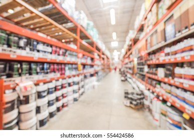 Blurred Large Hardware Store In America. Defocused Interior Home Improvement Retailer, Racks, Rows Of Interior Paint, Exterior Paint/stain, Floor Paint/stain Cans And Building Materials Up To Ceiling.