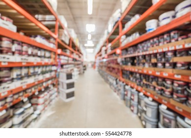 Blurred large hardware store in America. Defocused interior home improvement retailer, racks, rows of interior paint, exterior paint/stain, floor paint/stain cans and building materials up to ceiling.