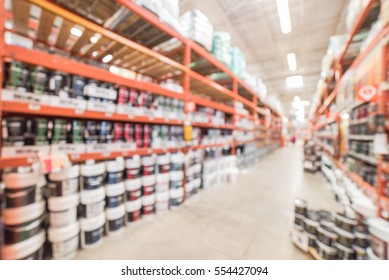 Blurred Large Hardware Store In America. Defocused Interior Home Improvement Retailer, Racks, Rows Of Interior Paint, Exterior Paint/stain, Floor Paint/stain Cans And Building Materials Up To Ceiling.