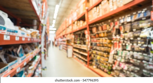 Blurred a large hardware store, tools and material. Defocused interior of home improvement retailer, racks of door hardware, weather proofing and lockset floor to ceiling. Customers shopping. Panorama - Shutterstock ID 547796395
