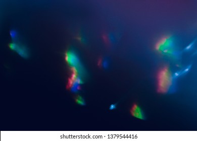 Blurred lens flare. Defocused colorful lights. Shiny glowing spots. Dark blue art abstract background.