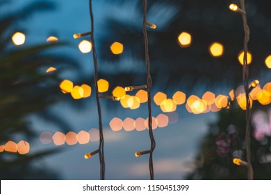 blurred light bokeh with coconut palm tree background on sunset, yellow string lights with bokeh decor in outdoor restaurant. - Powered by Shutterstock