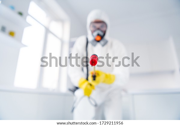 Blurred low angle view photo of sprayer\
cleaner hold latex gloves goggles coverall spray sanitize surface\
stop spreading ncov epidemic in house\
indoors