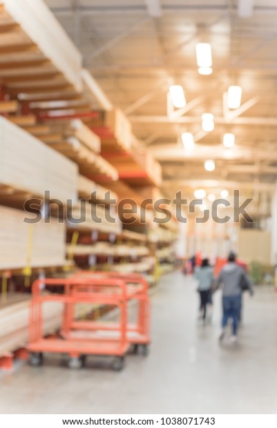Blurred lumber wholesale yard with divider cart\
at hardware store in USA. Rack fresh mill/cut wood timber in\
warehouse, pegboard, plywood, osb paneling, mdf. Industrial\
background. Customer\
shopping