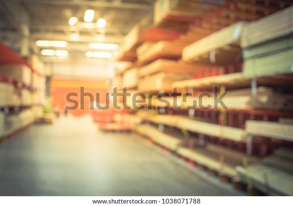 Blurred\
lumber wholesale yard with divider cart at hardware store in\
America. Rack of fresh mill/cut wood timber in warehouse, pegboard,\
plywood, osb paneling, mdf. Industrial\
background