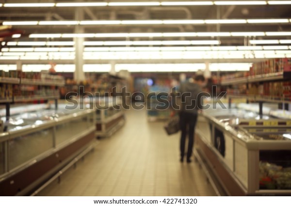 Blurred\
male by the fridge section in the\
supermarket