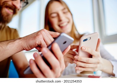 Blurred male and female bloggers checking mobile notification during friendly meeting for online networking in social media, millennial students reading web publications while browsing content
