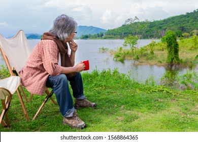 blurred man, asian senior man travel in forest, he drinking hot coffee at lakeside , happiness retirement activity, adventure and travel
