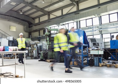 Blurred Motion Of Business People Wearing Reflective Clothing Walking In Metal Industry