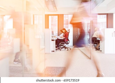 Blurred motion of businesswoman walking with colleagues working in background at office