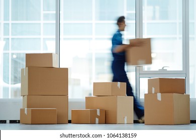 Blurred motion of contemporary worker with packed box walking to new office while delivering it to client