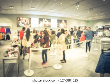 Blurred Motion Long Line Of Diverse Customers Waiting To Checkout At Apparel, Accessories Store In Texas, USA. Defocused Abstract Crowed People Retractable Stanchions Queue Barrier, Holiday Shopping