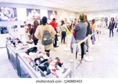 Blurred Motion Long Line Of Diverse Customers Waiting To Checkout At Apparel, Accessories Store In Texas, USA. Defocused Abstract Crowed People Retractable Stanchions Queue Barrier, Holiday Shopping