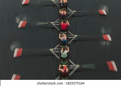 Blurred Motion Overhead View Of A Rowing Crew In A Sculling Boat On The Water, Mid Stroke