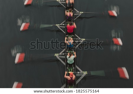 Blurred motion overhead view of a rowing crew in a sculling boat on the water, mid stroke