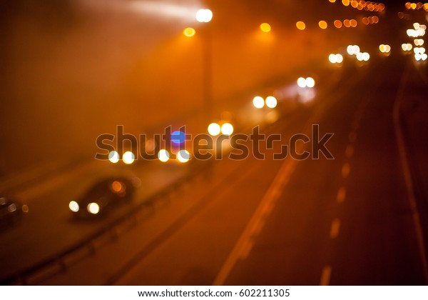 Blurred motion\
picture in Kiev at night in the fog. Kind of traffic on a busy\
street at night - the image has motion blur and soft focus. Blurred\
image of Kiev\'s evening\
traffic.