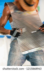 Blurred Movement Of A Man In A Straw Hat Wearing And Playing A Metal Washboard Vest