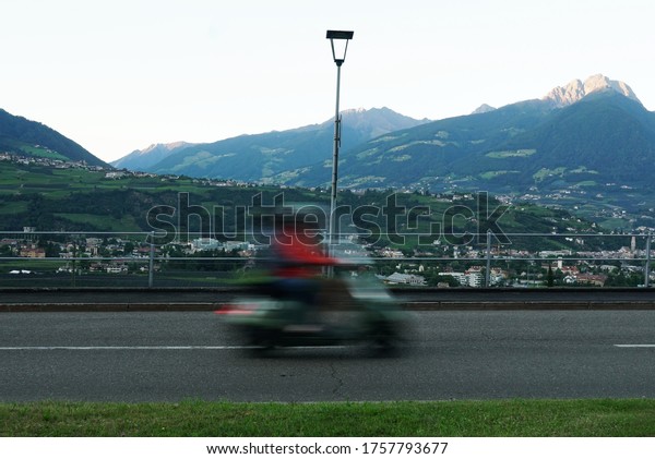 A\
blurred moving motorcycle on the road in Meran\
city