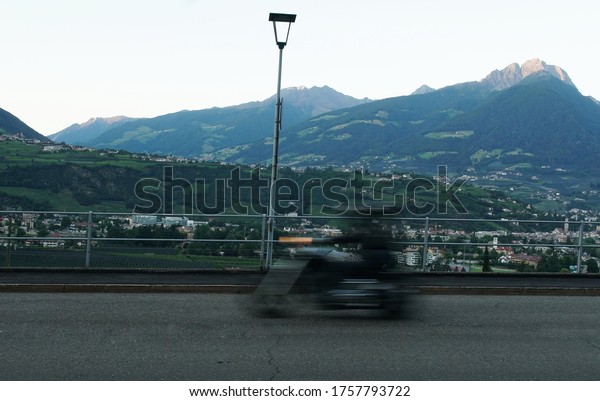 A\
blurred moving motorcycle on the road in Meran\
city