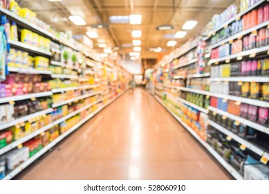 Blurred Natural Coffee, Tea, Water, Bottled Tea, Energy Drinks Aisle In Store At Houston, Texas, US. Wide View Supermarket Shelves, Variety Of Products Display With Bokeh Light. Customer Shopping.