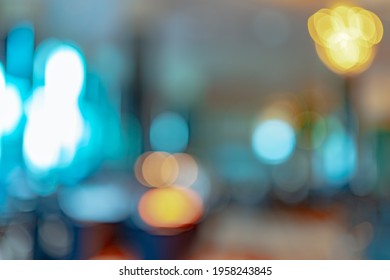 Blurred Orange, Yellow, And Blue Light Bokeh Abstract Background. Defocused Orange And White Light On Coffee Shop Or Office Interior. Bokeh Background Of Modern Light Decoration In The Building.