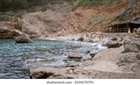 Blurred outdoor scene at a mallorca beach in spain with people enjoying the seashore and natural rocky landscape on a sunny day - Powered by Shutterstock