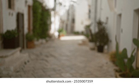 Blurred outdoor view of a sunny narrow street in locorotondo, puglia, italy, europe, showcasing cobblestones, whitewashed buildings, plants, and a tranquil village atmosphere. - Powered by Shutterstock