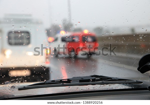Blurred Paramedics van at accident scene, rain\
on windshield