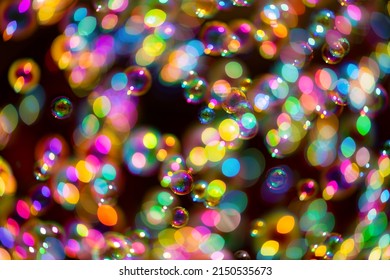 Blurred and partially unfocused gliding soap bubbles isolated on black background with reflection effects. Extremely thin film enclosing air that forms a hollow sphere with an iridescent surface.