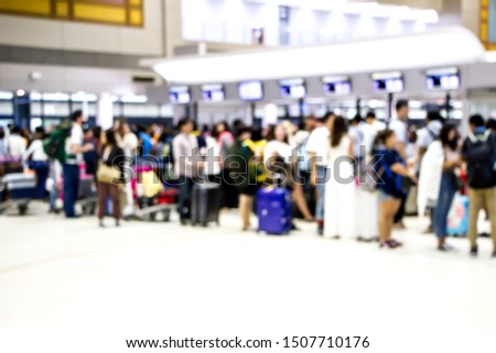 blurred passengers queuing for checking in at the airport