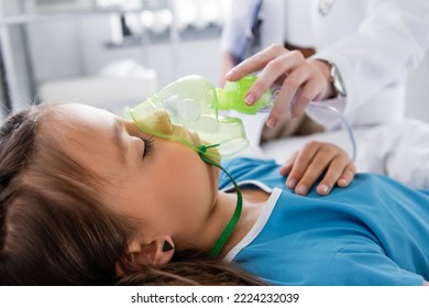 Blurred pediatrician holding oxygen mask near sick child in hospital - Powered by Shutterstock