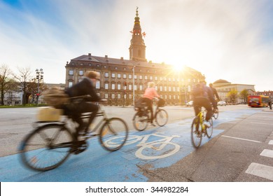 Blurred people going by bike in Copenhagen, with Christiansborg palace on background. Many persons prefer biking instead of taking car or bus to move around the city. Urban lifestyle concept.