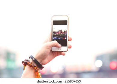 Blurred People Hand Hold Phone Take Photo In Concert And Travel Up To Sky With Purple Light Background, Internet And Communication Lifestyle.