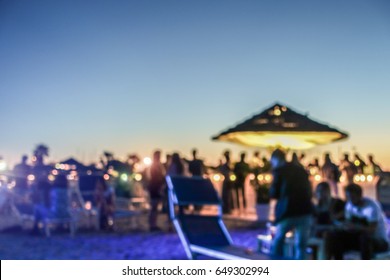 Blurred people having sunset beach party in summer vacation - Defocused image - Concept of nightlife with cocktails and music entertainment - Warm filter with blurry bokeh