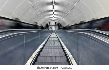 Blurred people on escalator. London subway station at rush hour.