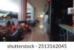 Blurred people sitting in a shopping mall food court with bokeh background and out-of-focus corridor